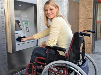 Eine Rollstuhlfahrerin benutzt einen Geldautomaten.