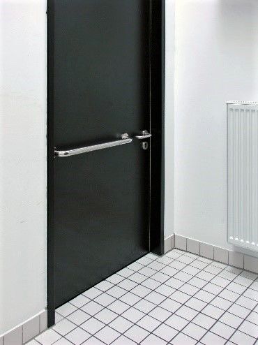 Auf der Innenseite einer Tür ist eine lange Zuziehstange waagerecht in Höhe des Türdrückers montiert.