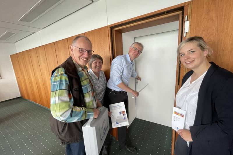 Das Bild zeigt von links nach rechts: Wolfgang Bennewitz und Elisabeth Grieseler-Middendorf (beide vom Behindertenbeirat), den Fachdezernenten Ludger Trepper der gerade die Türleibung misst und Daria Frank von der Agentur Barrierefrei NRW.